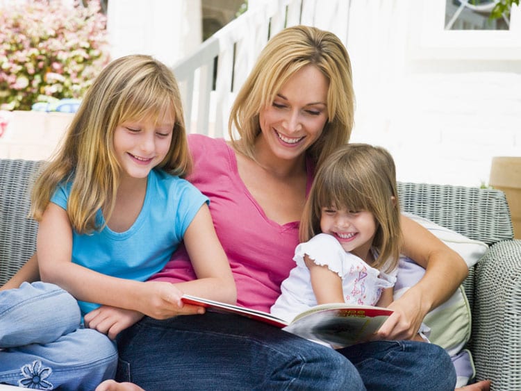 mother and two daughters reading a book