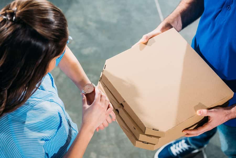 Woman checking her watch when meeting courier with pizzas